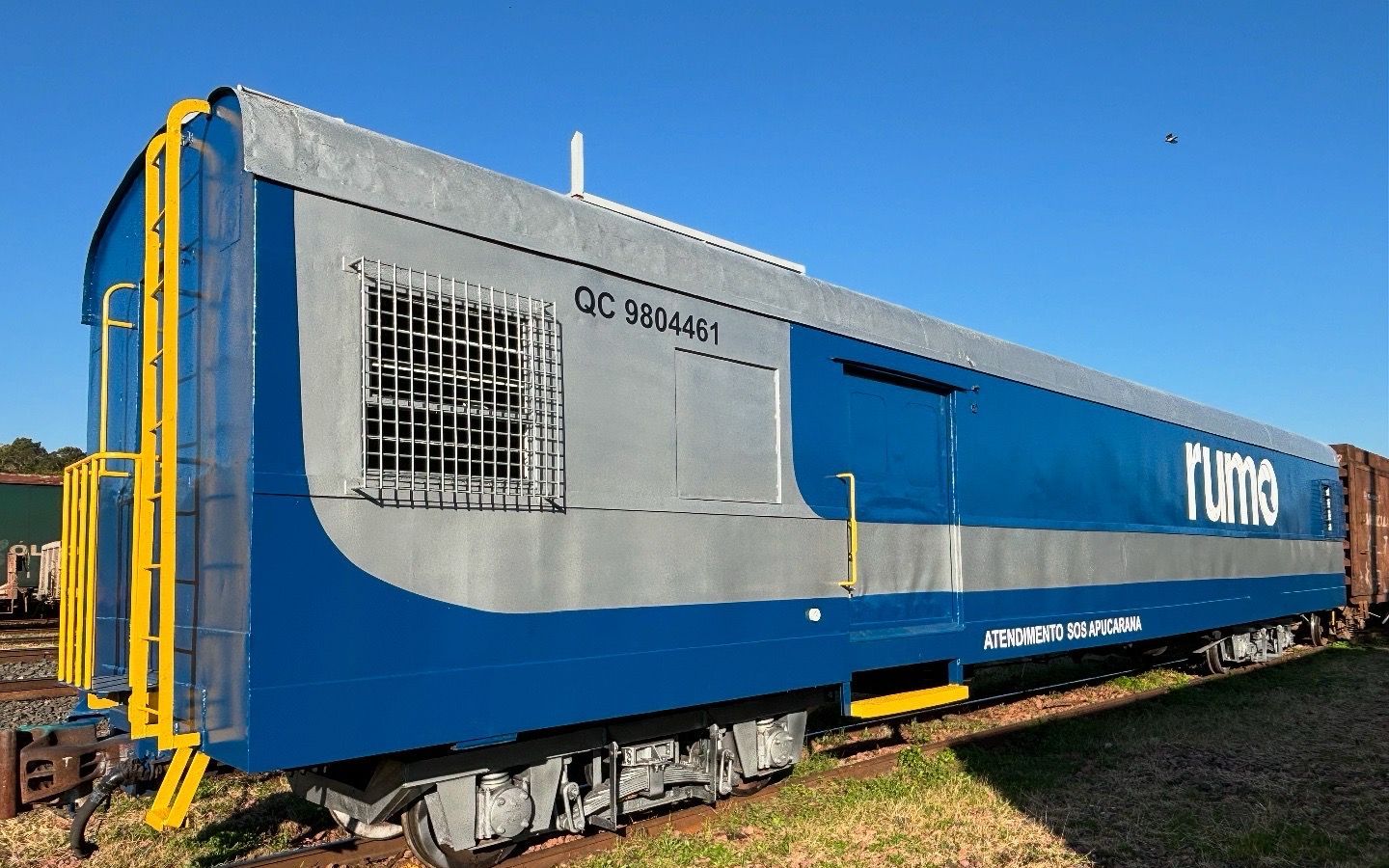 Vagão QC 9804461 da Rumo reformado pela Tec Rail, pintado de azul e cinza, sobre os trilhos